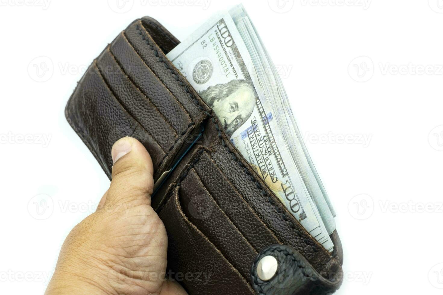 Mano sujetando la billetera en fajos de billetes de 100 dólares estadounidenses sobre fondo blanco. foto