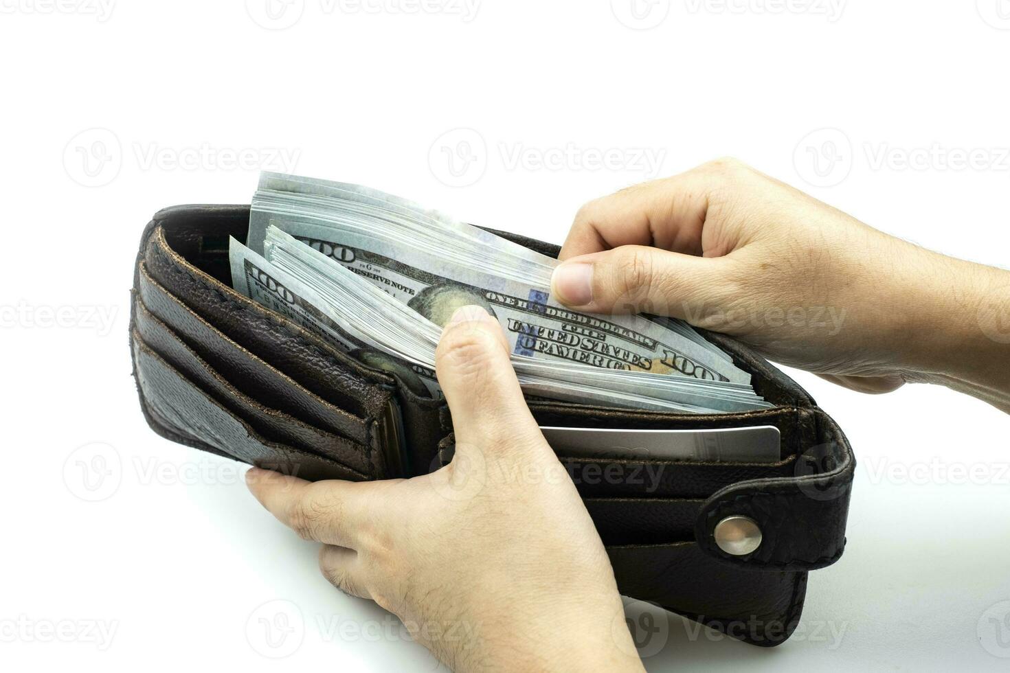 Hand holding wallet on bundles of 100 US dollars banknotes on white background photo