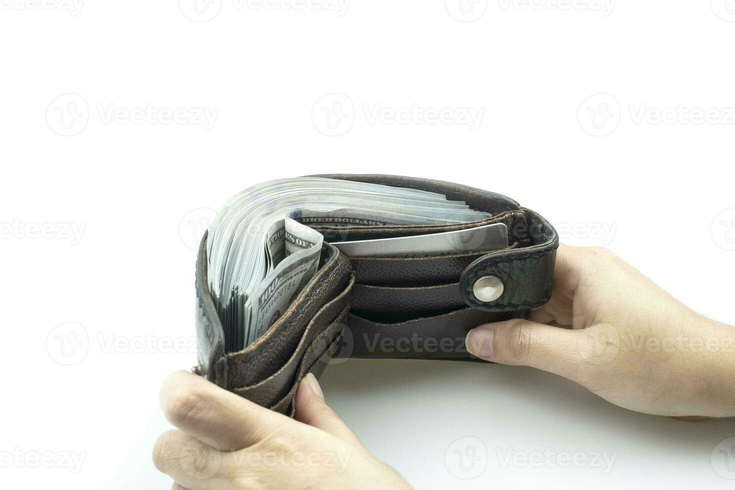 Hand holding wallet on bundles of 100 US dollars banknotes on white background photo