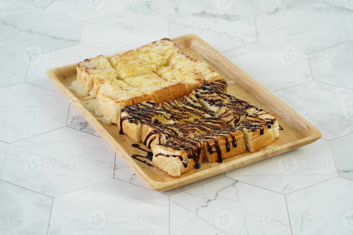 tostadas con leche condensada azucarada y sirope de chocolate en placa de madera. foto