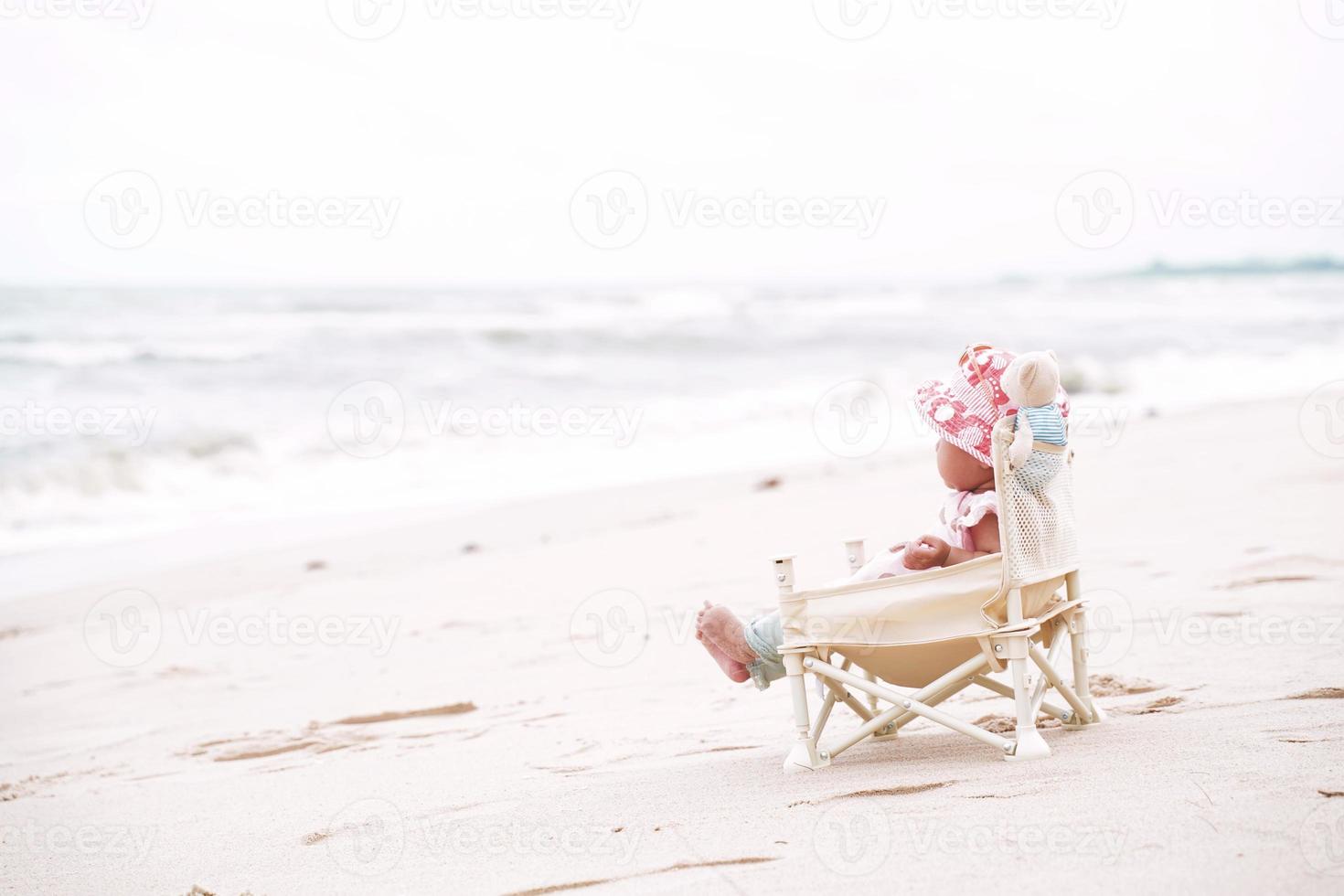 niña asiática sentada en la silla de playa. foto