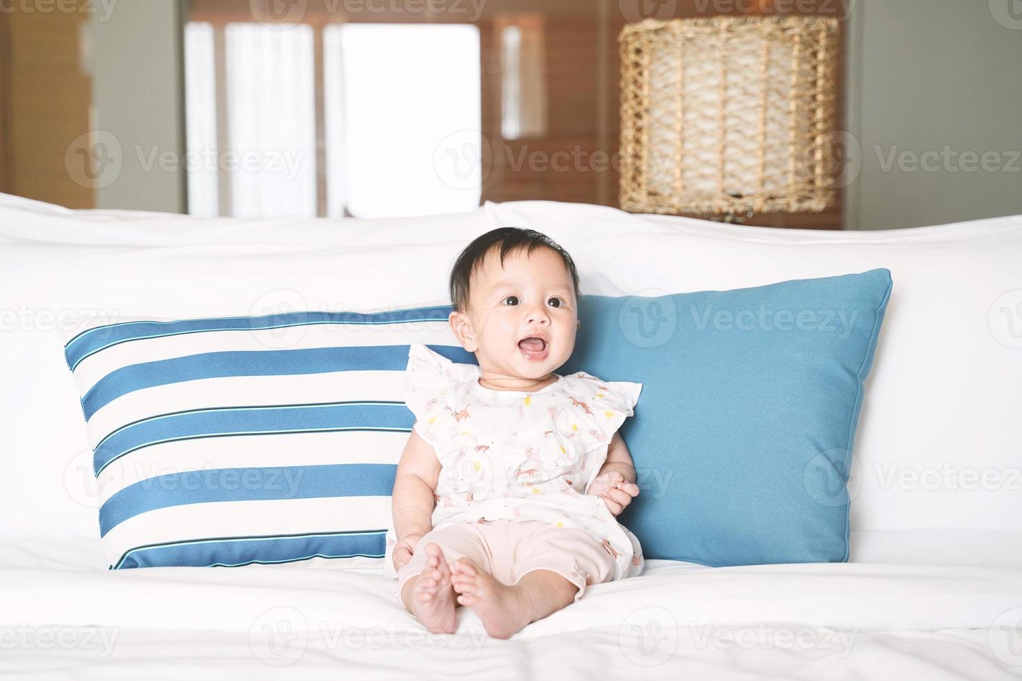 linda niña sonriente sentada en la cama. foto