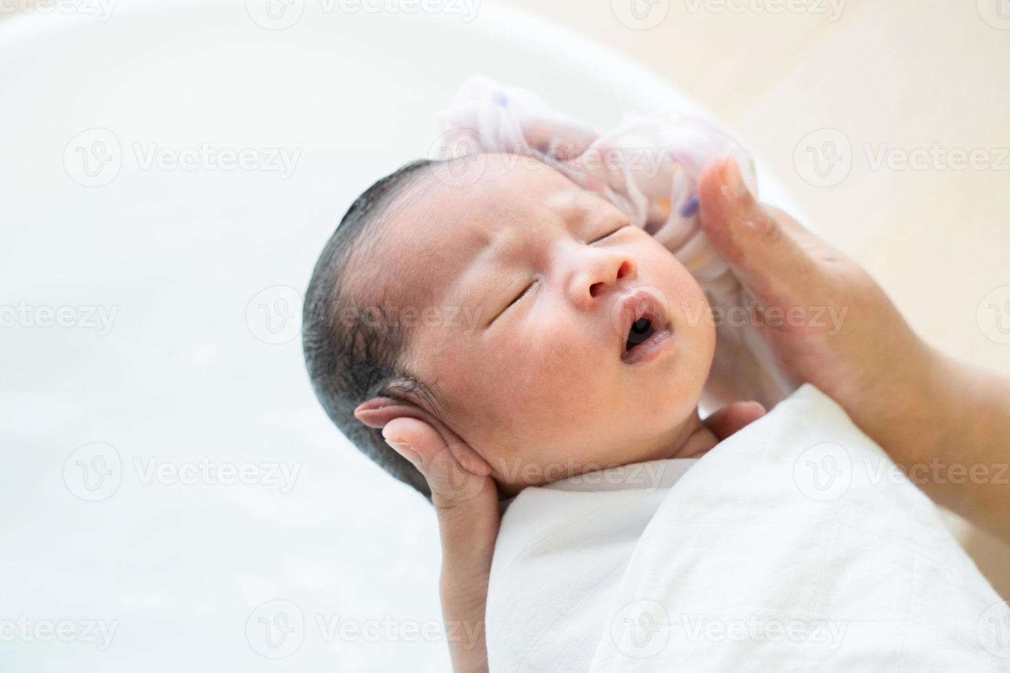 la madre está lavando el pelo del bebé. mamá limpiando el cabello de su bebé. foto