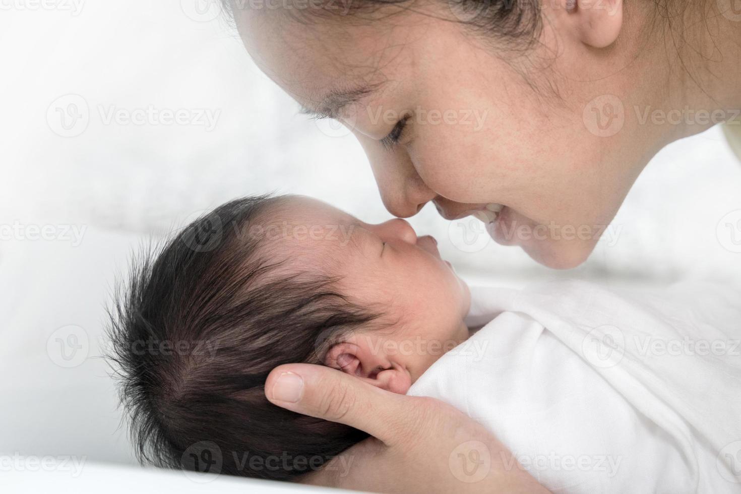 Cerrar joven madre asiática besando a su bebé recién nacido. amor de mamá recién nacido. foto