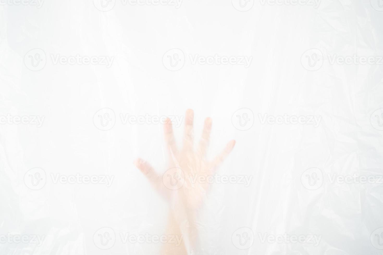 Blurred hand pushing behind the plastic sheet on white background. Stop using the plastic concept. photo