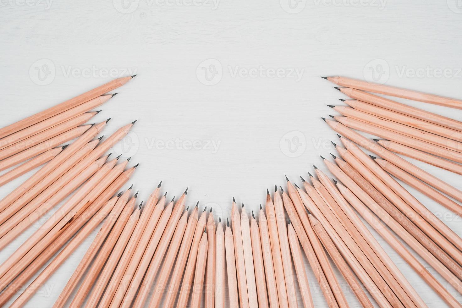 Wooden pencils arranged in a half circle on white table. photo