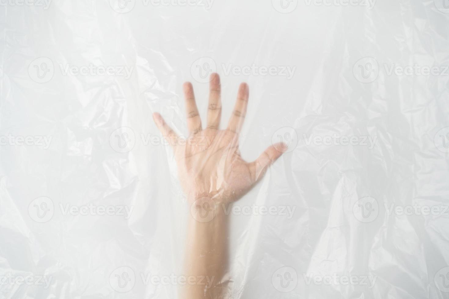 Hand pushing behind the plastic sheet on white background. Stop using the plastic concept. photo