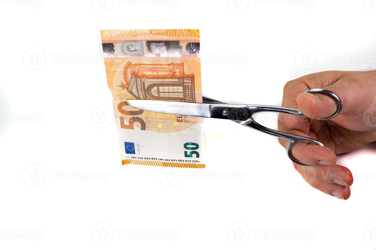 man cutting 50 euro banknotes with scissors photo