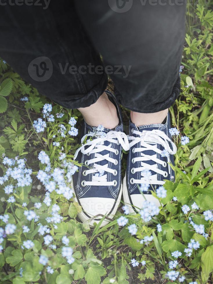 piernas en zapatillas azules sobre la hierba foto