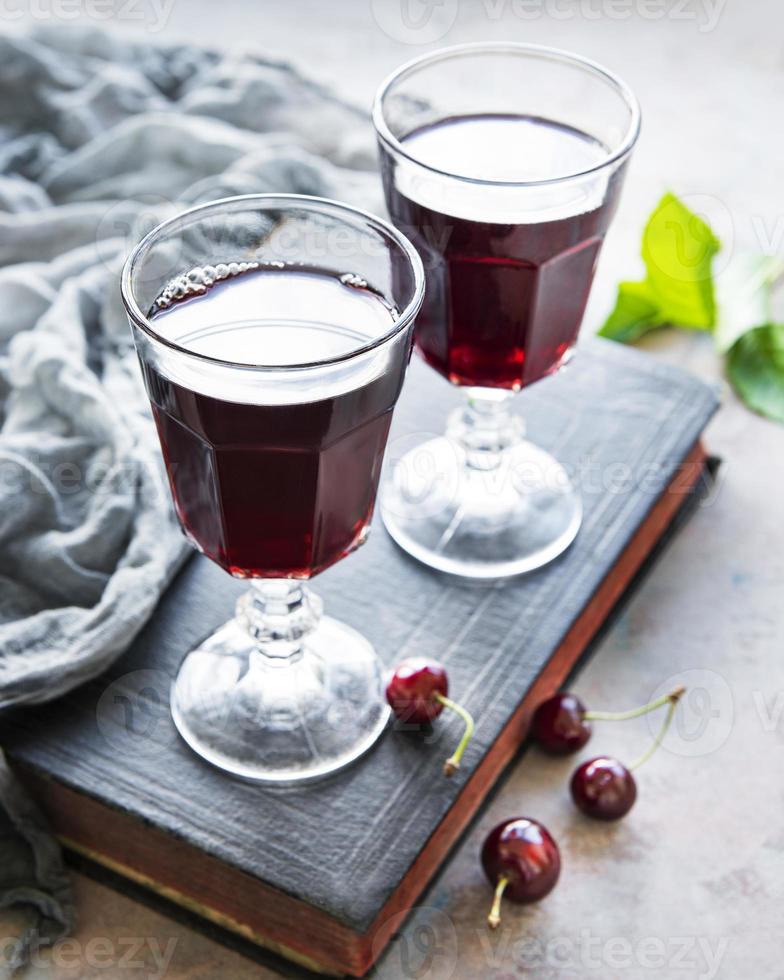 Cherry liqueur in a glass and fresh fruits photo