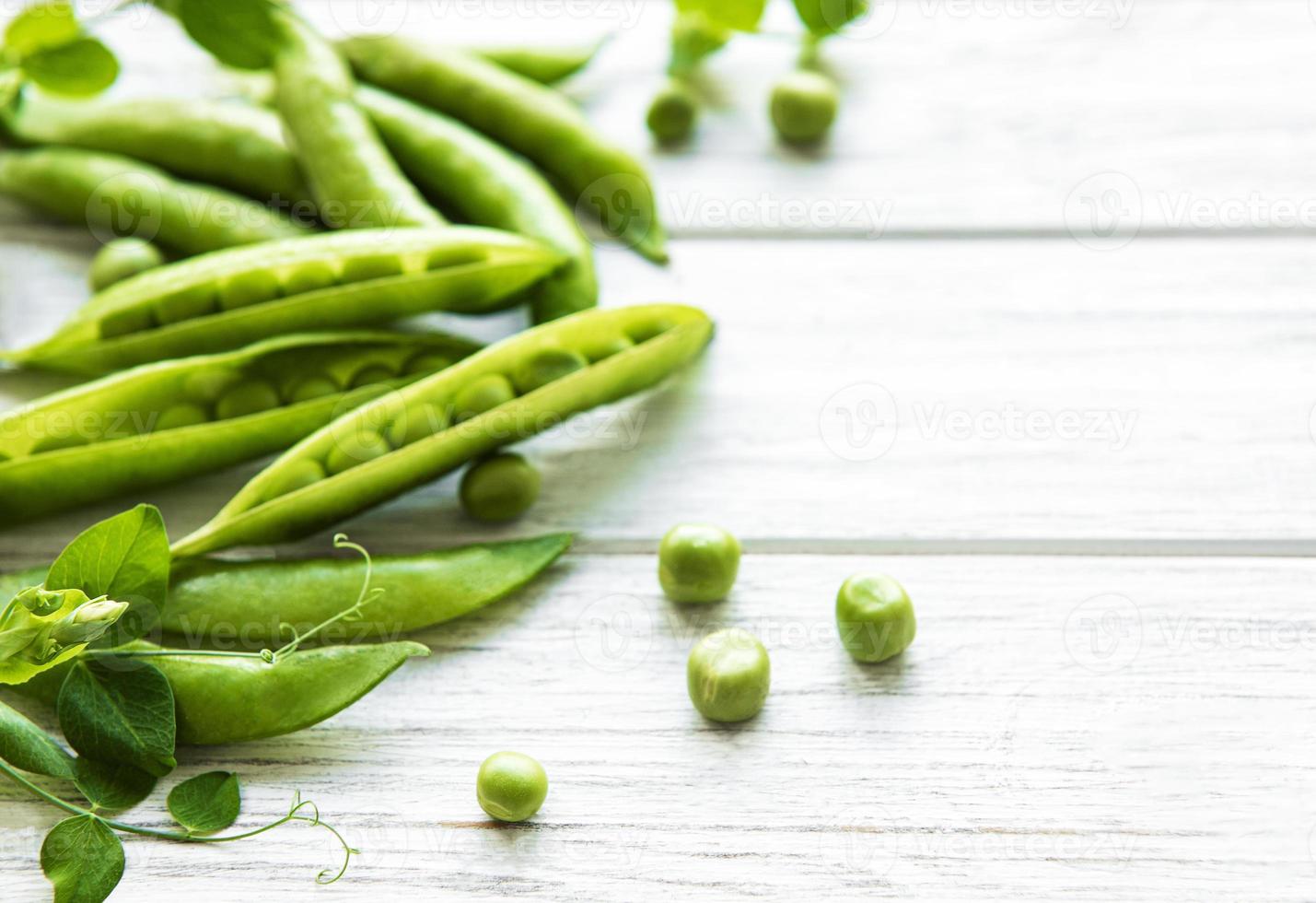 guisantes verdes sobre un fondo de madera blanca. fondo de comida sana foto