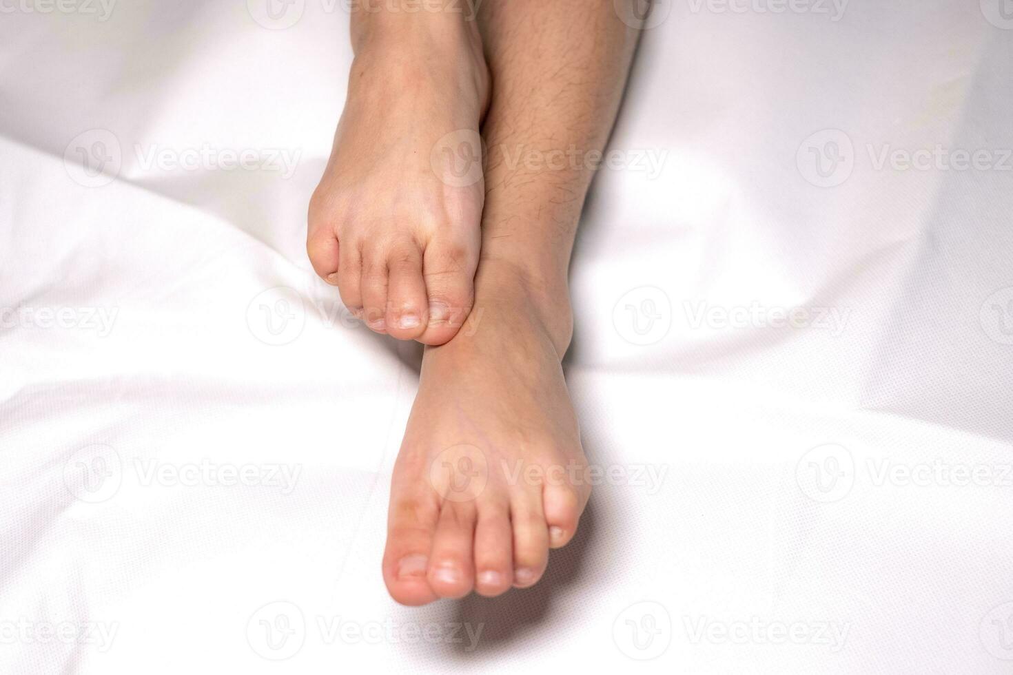 Mujer flexión del pie en las sábanas de color blanco foto