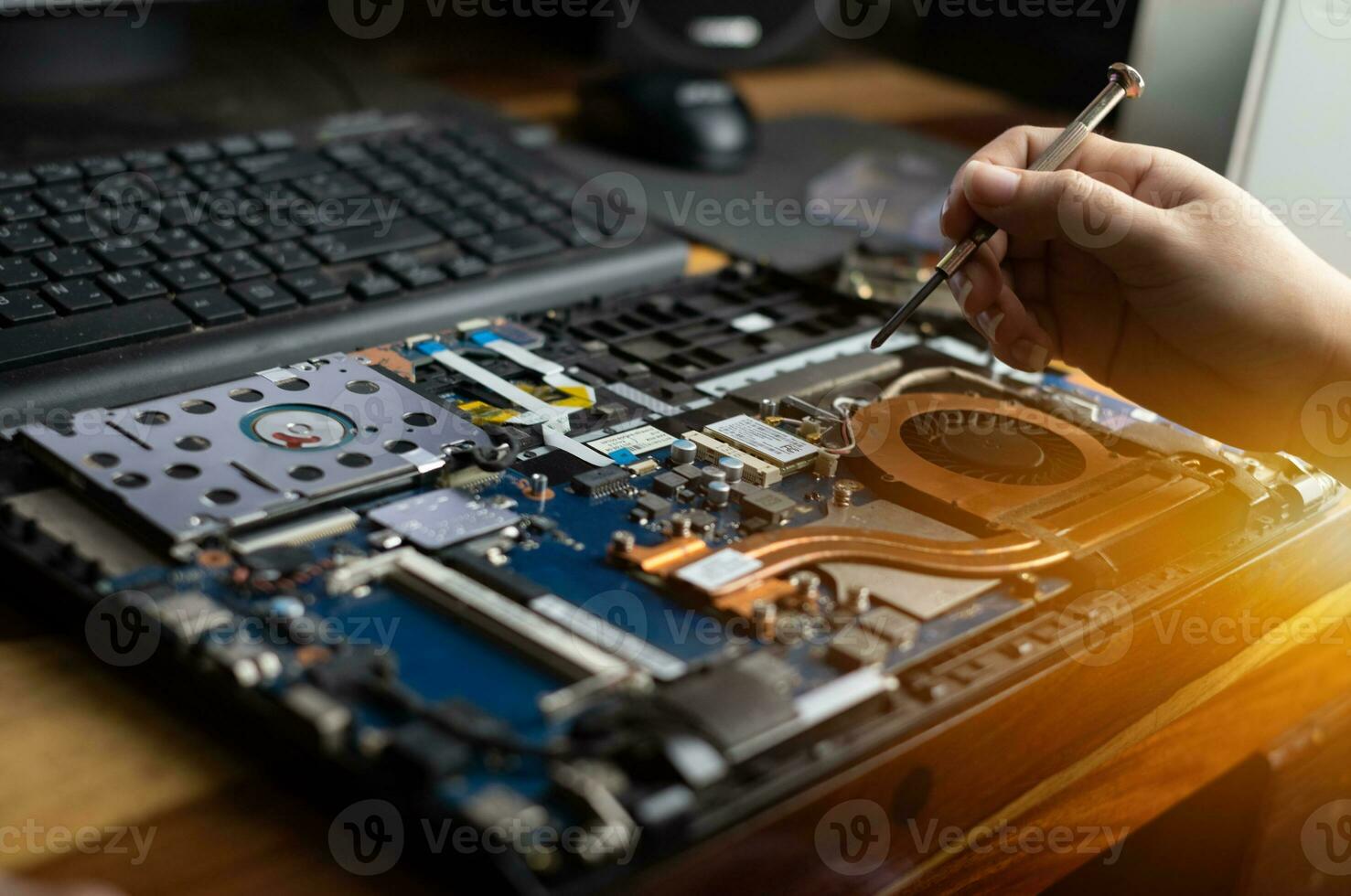 Technician repairing broken laptop notebook computer with a screwdriver photo