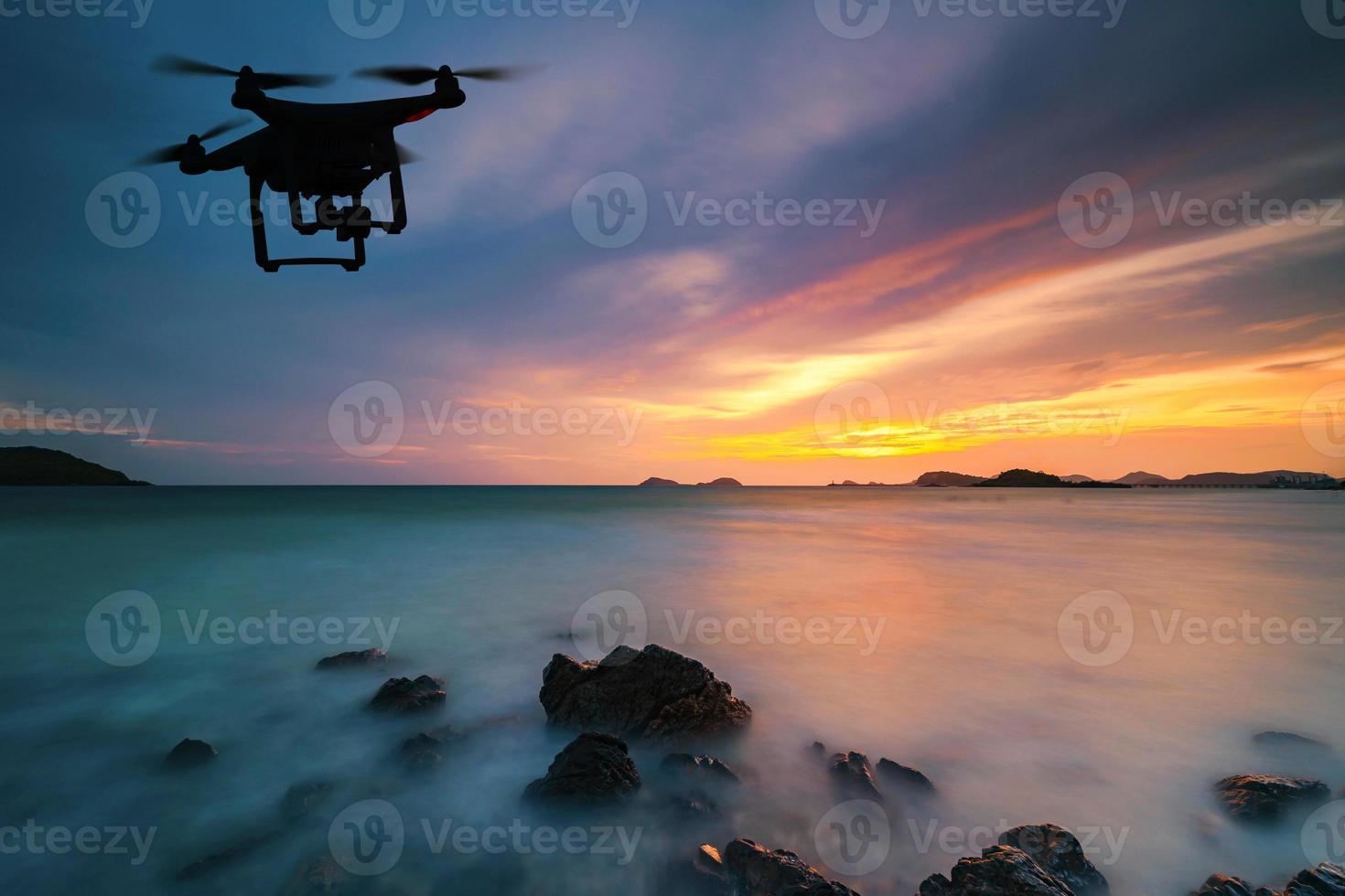 Silhouette of drone flying over sea at sunset photo