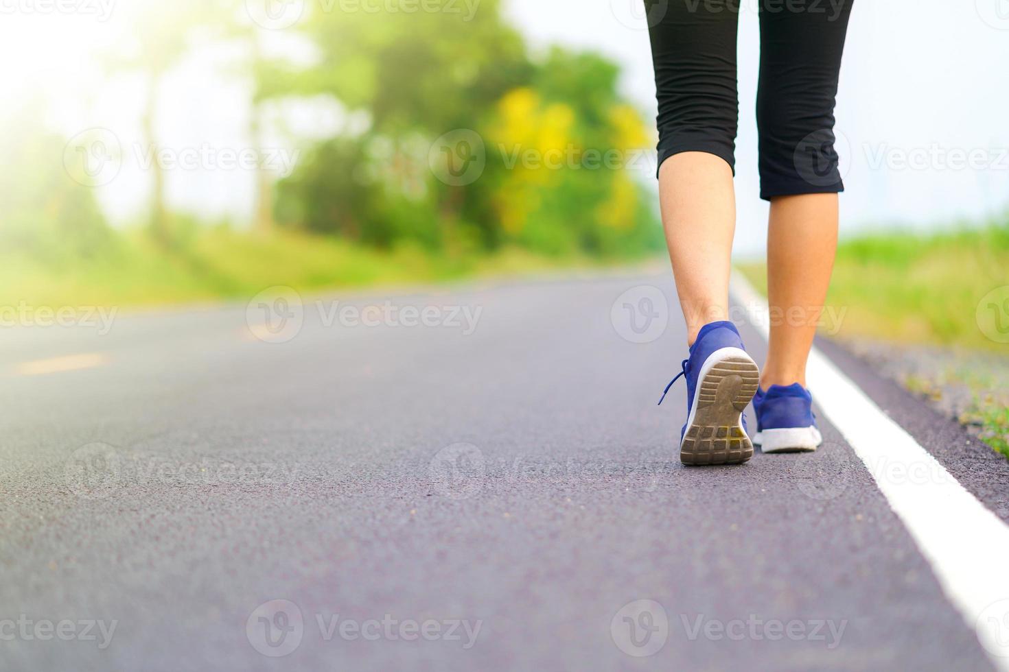 Piernas de mujer caminando en el parque, corredora corriendo en la carretera exterior foto