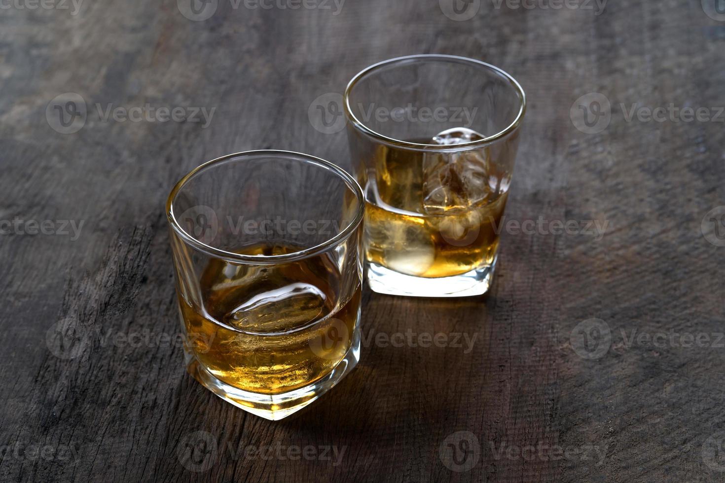 Top view of Whiskey with ice in glass on wooden table photo