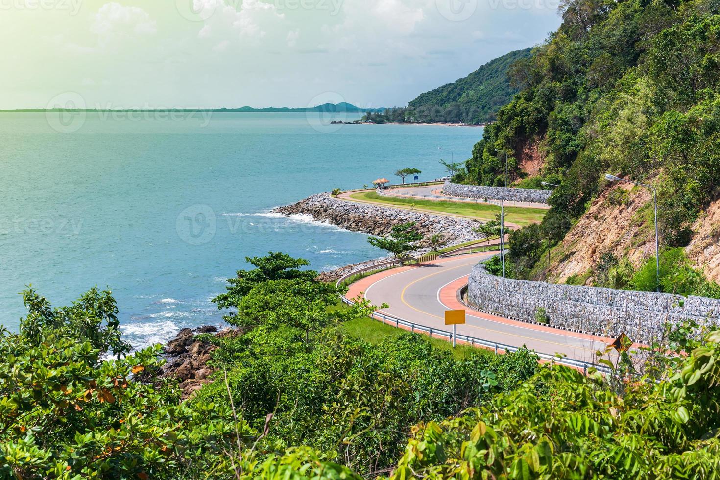 Road beside the ocean and mountain under blue sky photo