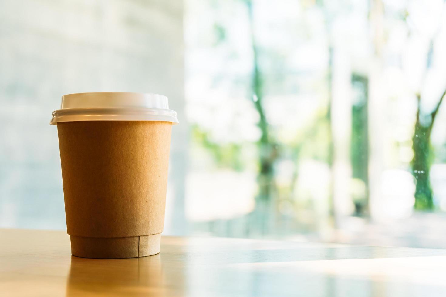 Hot latte coffee in paper cup on table in cafe photo