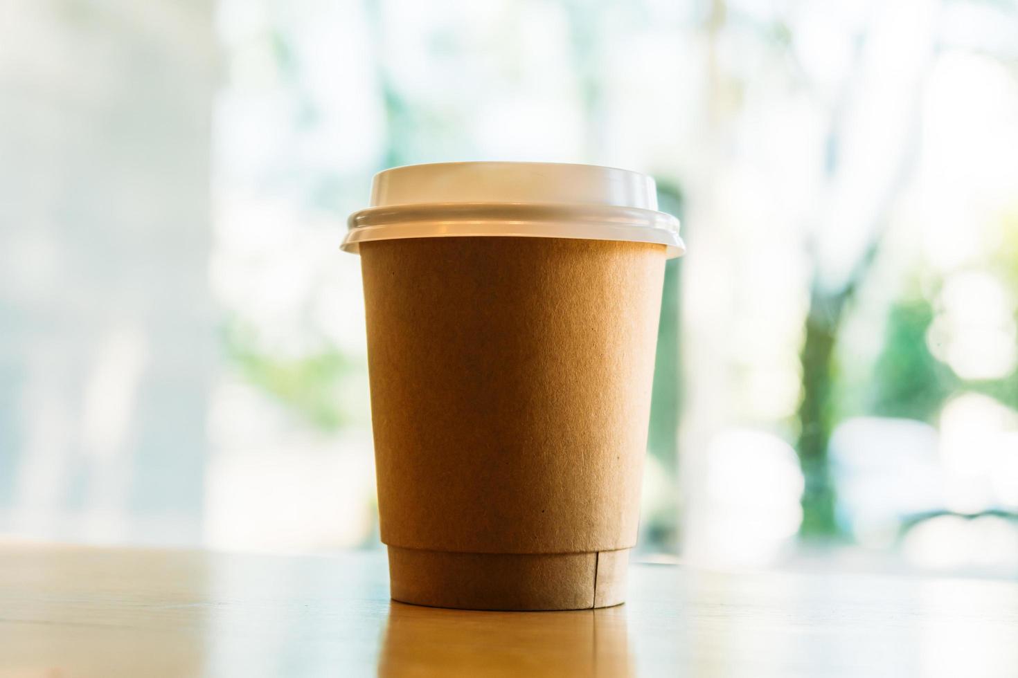 Hot latte coffee in paper cup on table in cafe photo