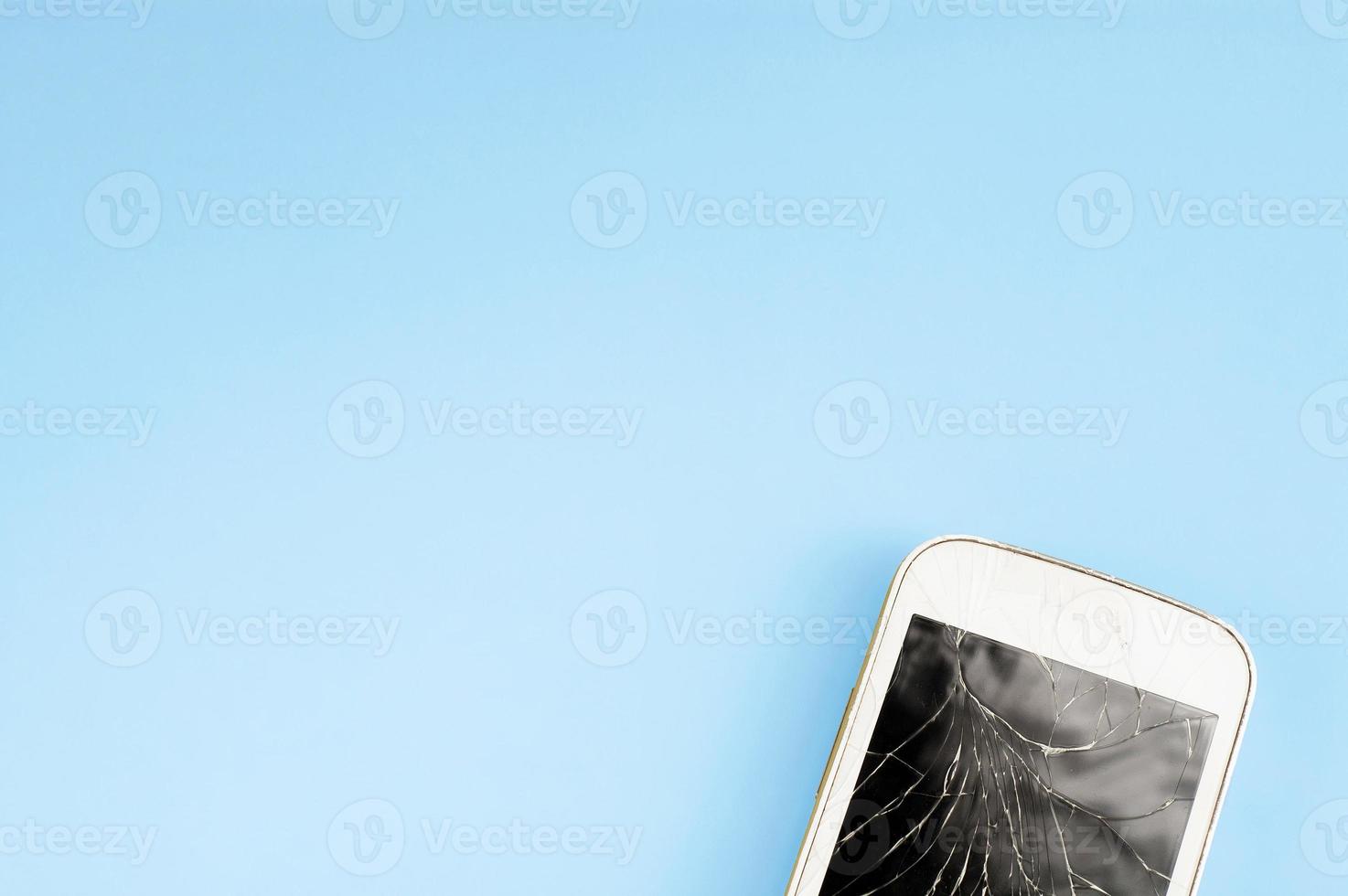 A broken touchscreen cell phone on blue background with free copy-paste space for text photo