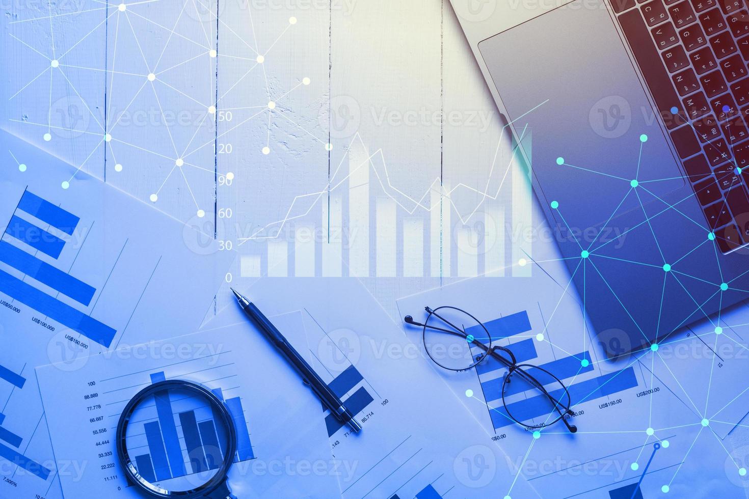 Magnifying glass and documents with analytics data lying on table,selective focus photo