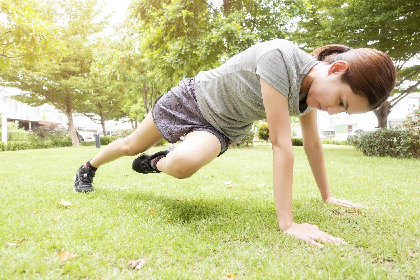 Beautiful sporty woman is doing exercises in green park photo