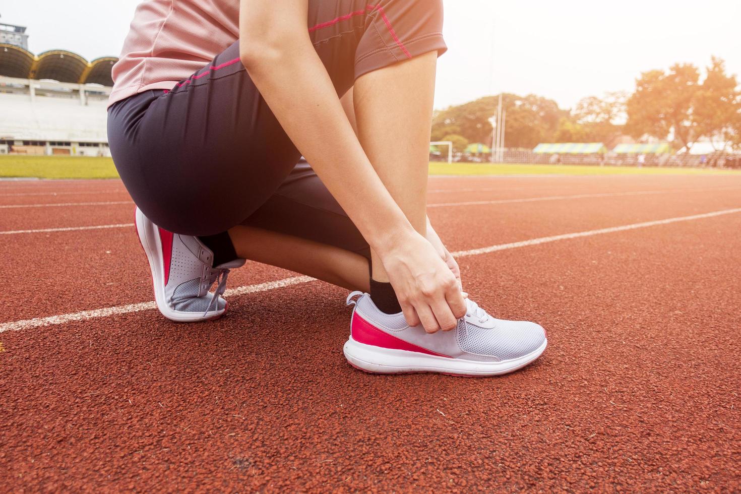 Close up woman is tie shoe in sport field photo