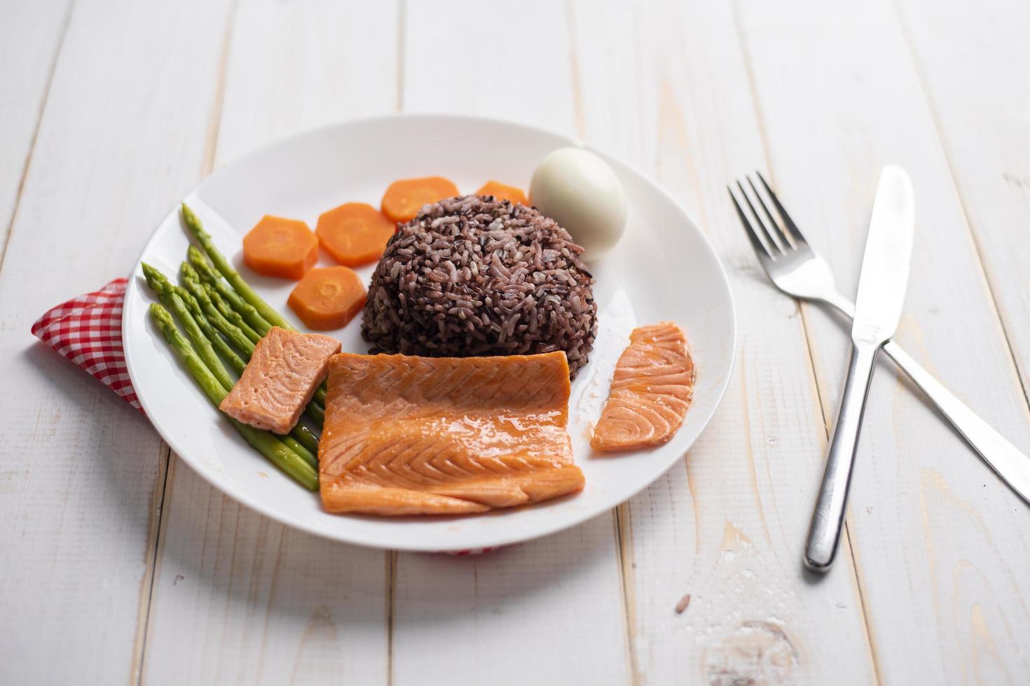 Concepto de comida sana, salmón con arroz y verduras sobre fondo de madera foto