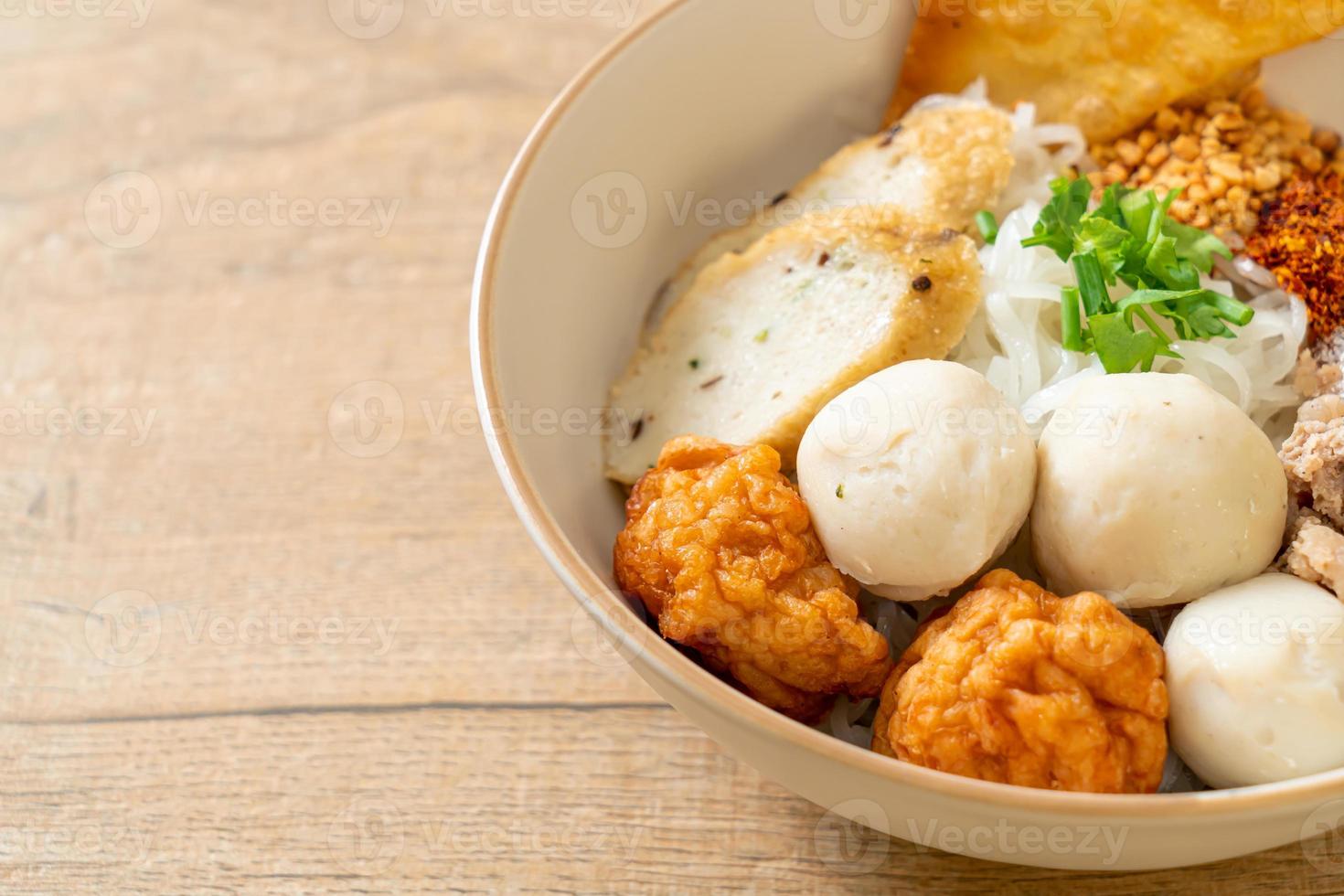 Fideos de arroz planos pequeños picantes con bolas de pescado y bolas de camarones sin sopa - estilo de comida asiática foto