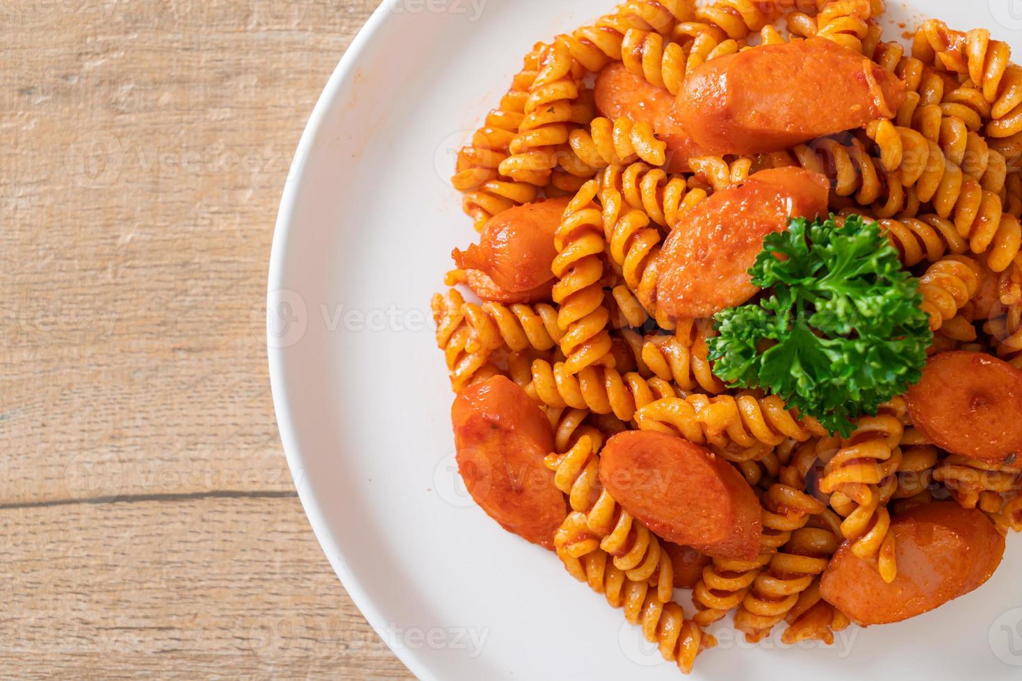 pasta en espiral o spirali con salsa de tomate y salchicha - estilo de comida italiana foto