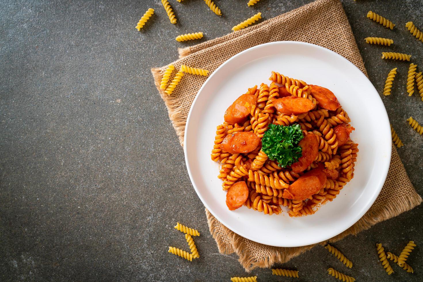 pasta en espiral o spirali con salsa de tomate y salchicha - estilo de comida italiana foto