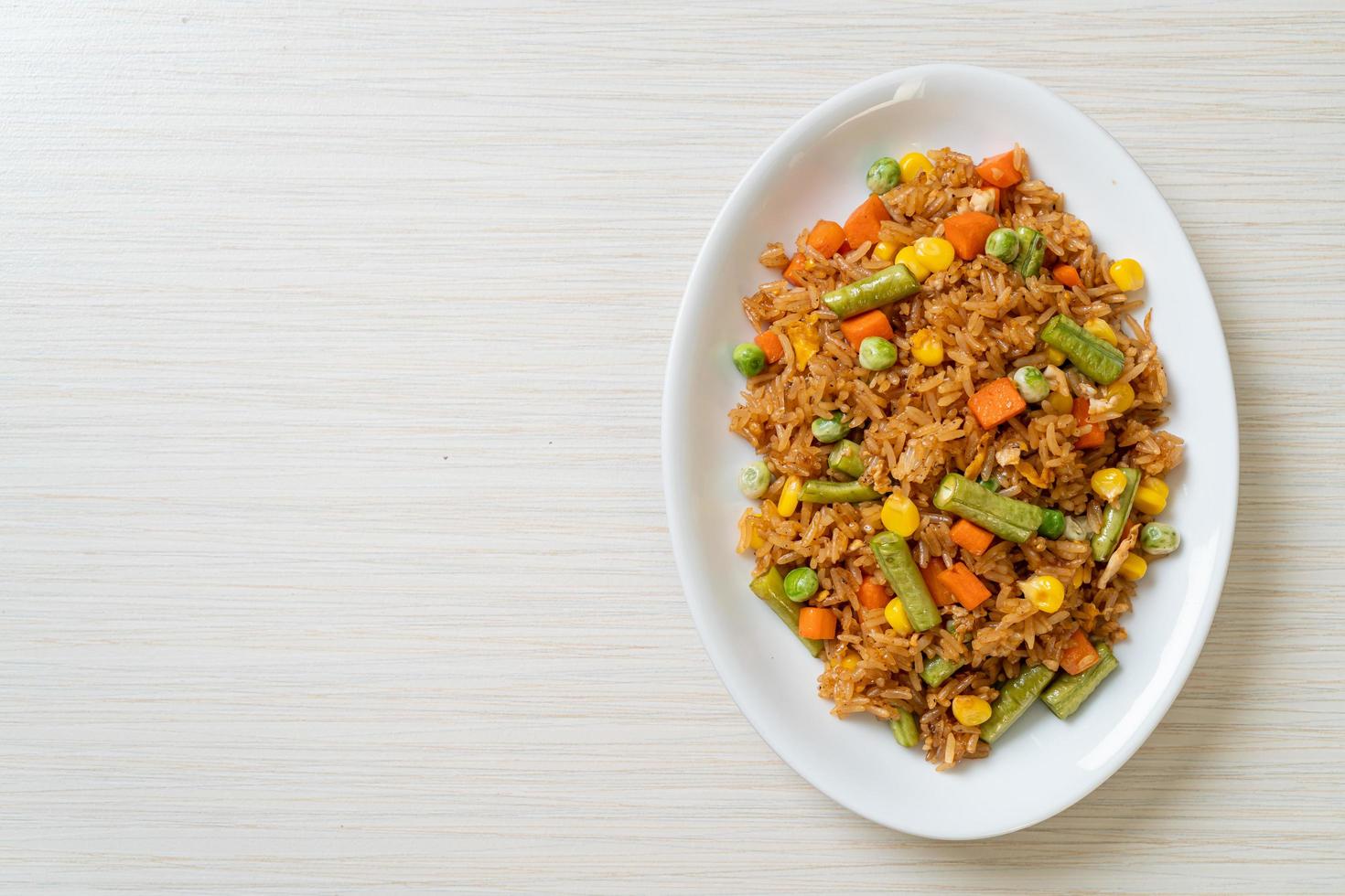 arroz frito con guisantes, zanahoria y maíz - estilo de comida vegetariana y saludable foto