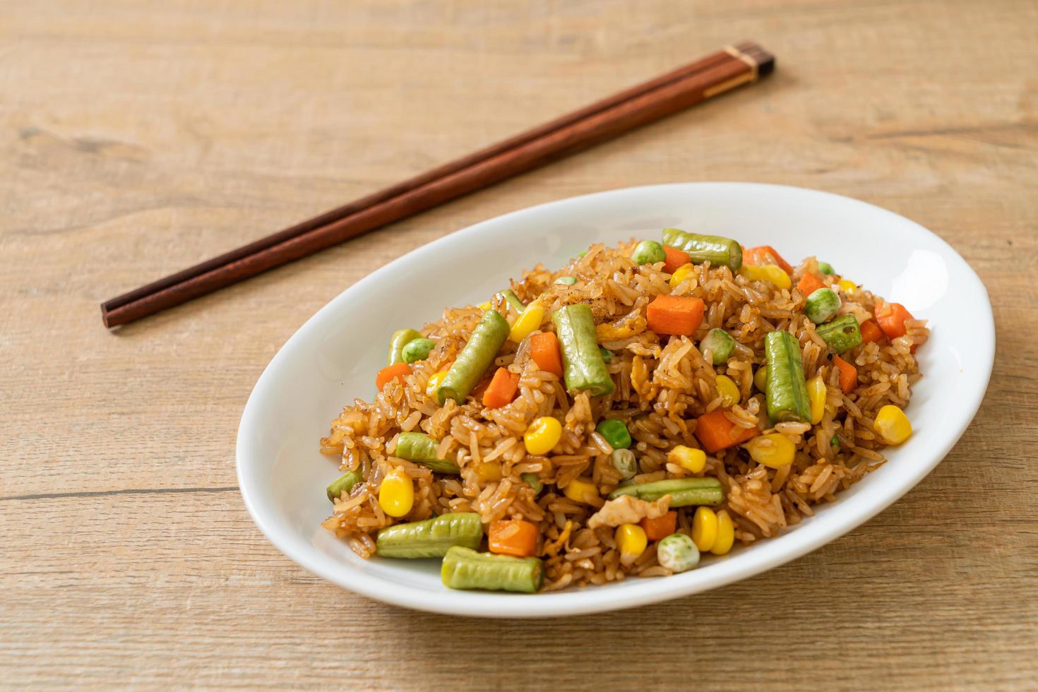 arroz frito con guisantes, zanahoria y maíz - estilo de comida vegetariana y saludable foto