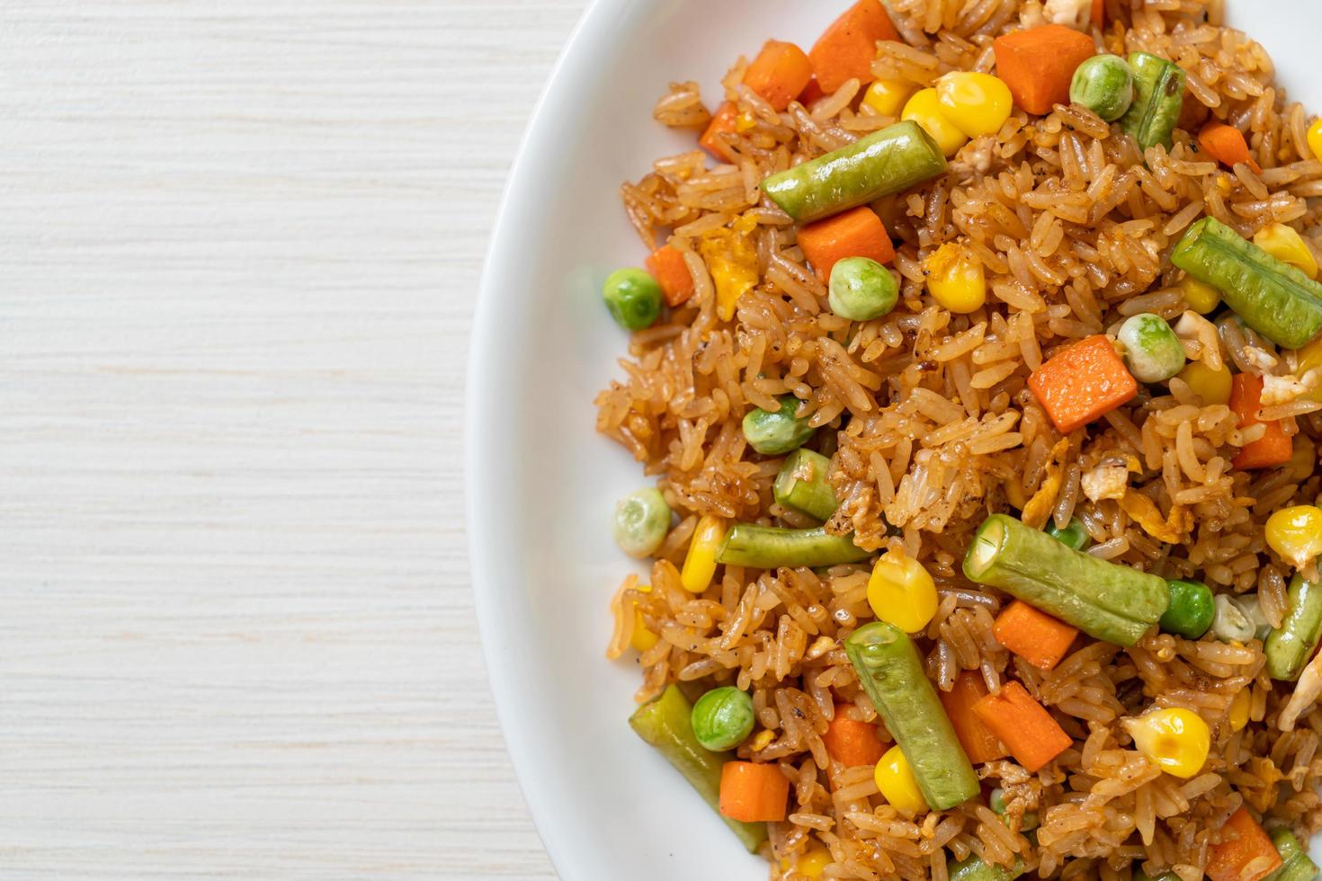 arroz frito con guisantes, zanahoria y maíz - estilo de comida vegetariana y saludable foto