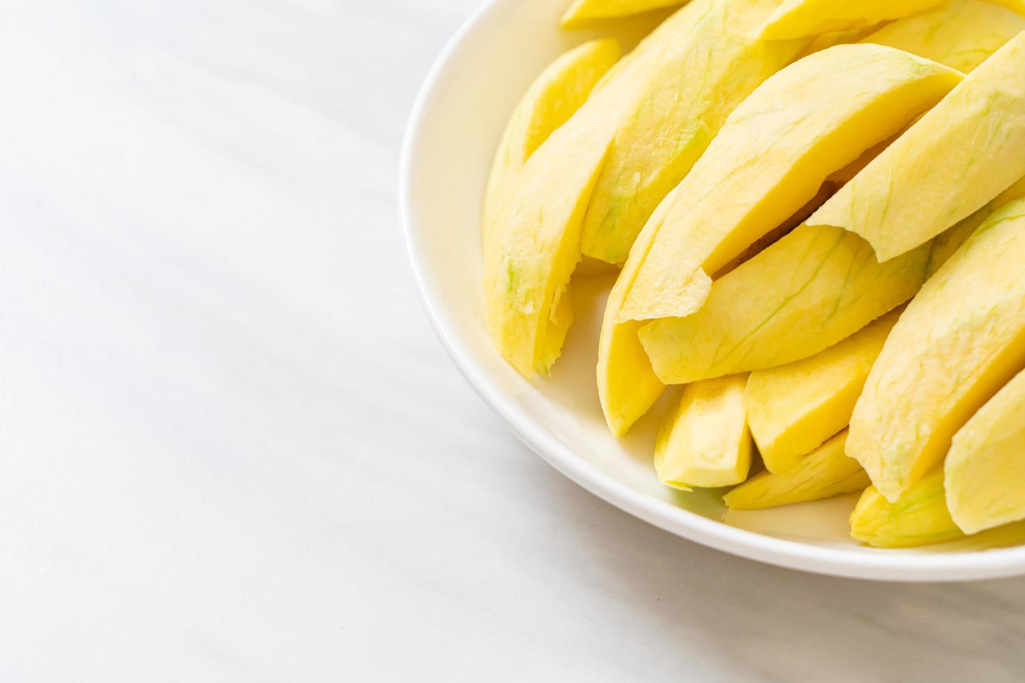 Fresh green and golden mango sliced on plate photo