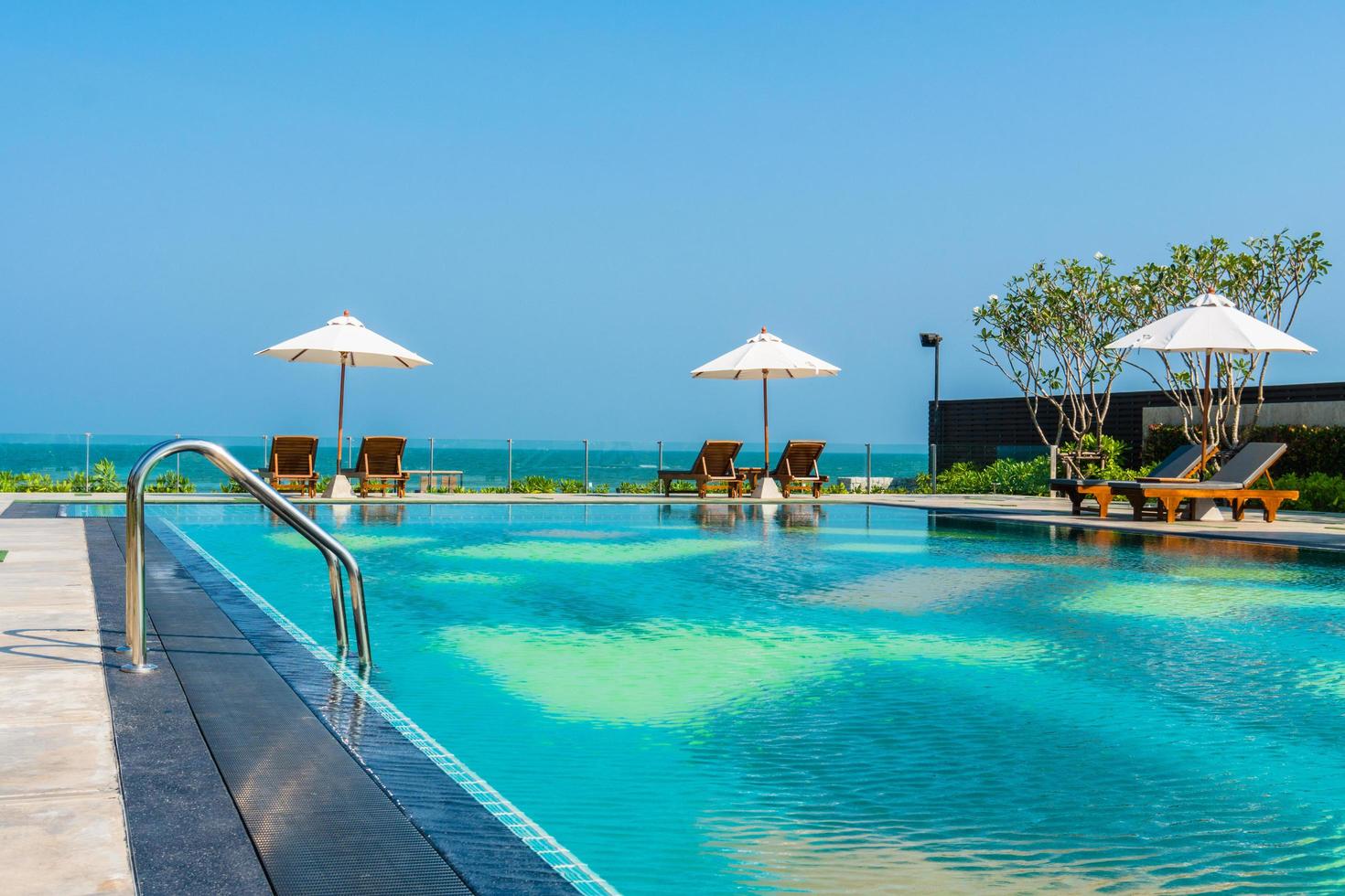 Beautiful umbrella and chair around swimming pool in hotel and resort photo