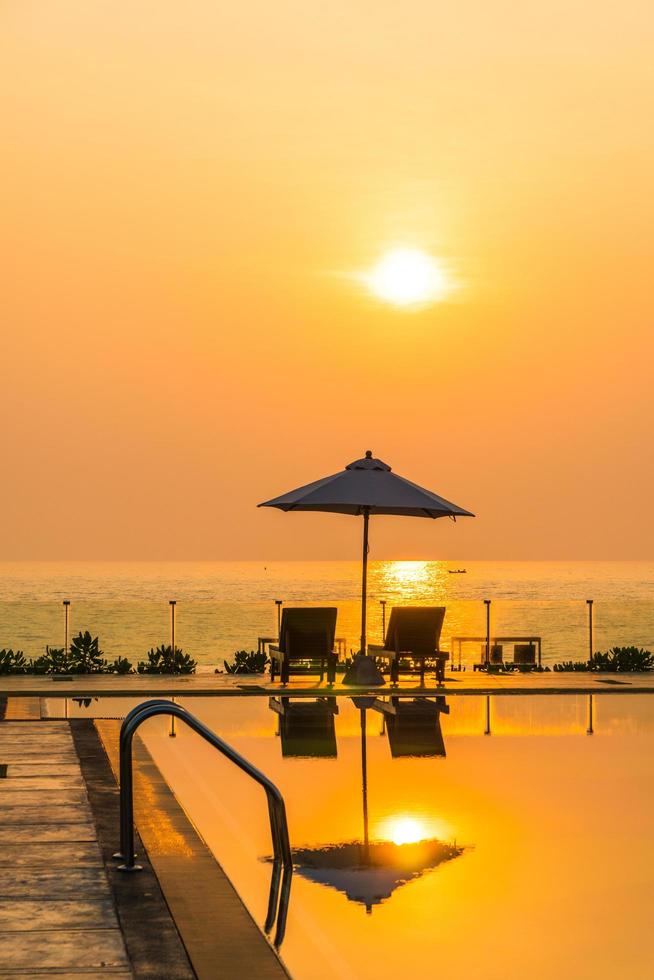 Hermosa sombrilla y silla alrededor de la piscina en el hotel y resort foto