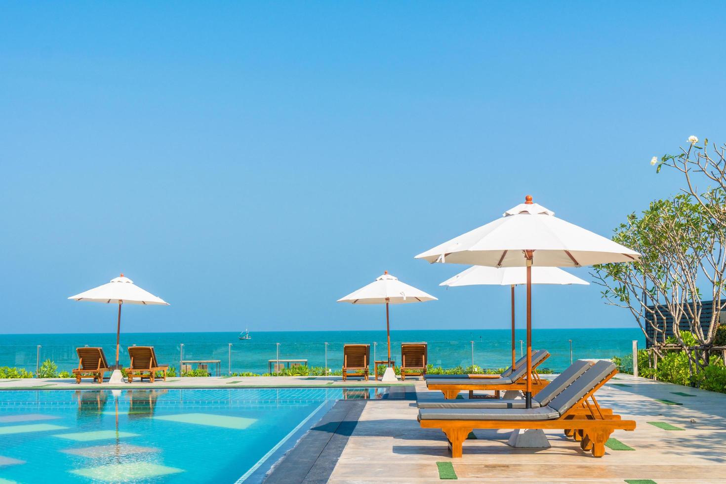 Hermosa sombrilla y silla alrededor de la piscina en el hotel y resort foto