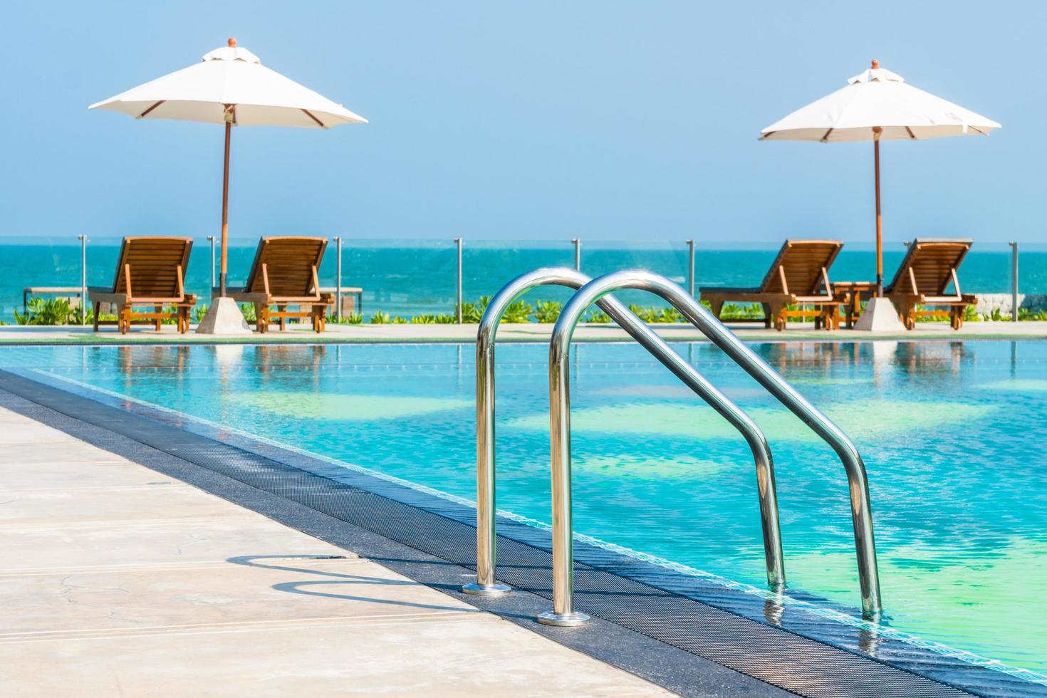 Hermosa sombrilla y silla alrededor de la piscina en el hotel y resort foto