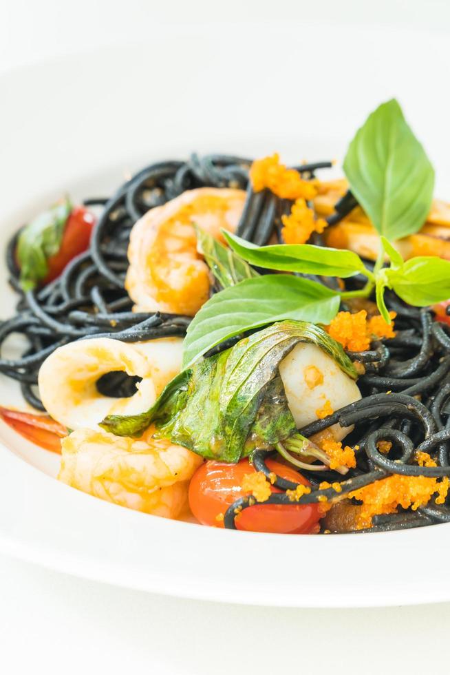 espaguetis negros con mariscos en plato blanco foto