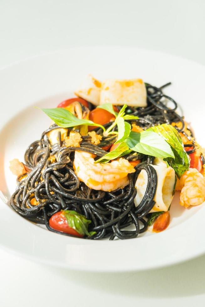 espaguetis negros con mariscos en plato blanco foto