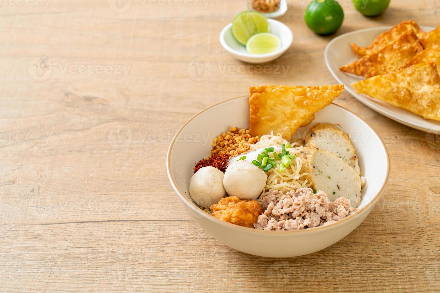 Fideos de huevo picantes con bolas de pescado y bolas de camarones sin sopa - estilo de comida asiática foto