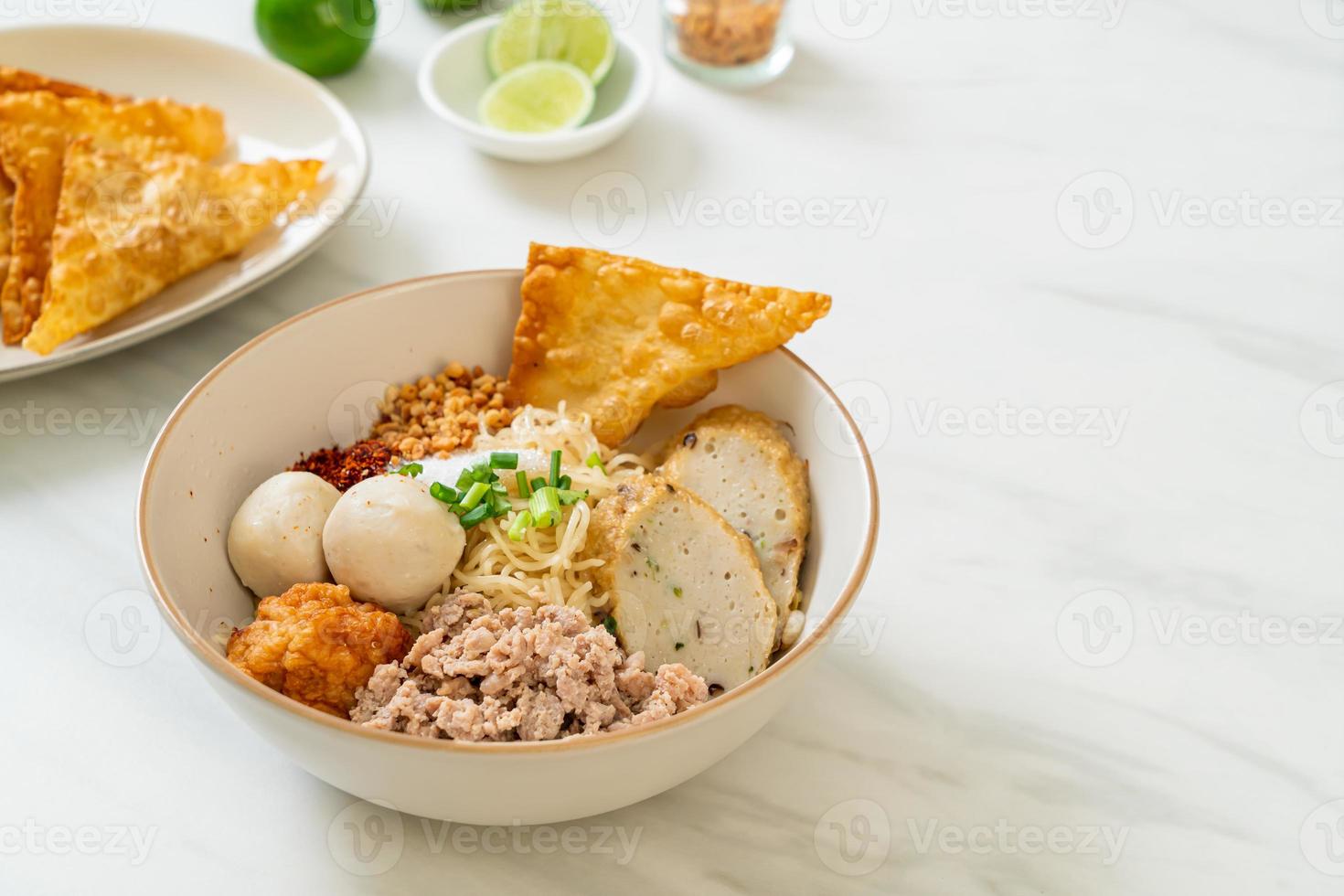 Fideos de huevo picantes con bolas de pescado y bolas de camarones sin sopa - estilo de comida asiática foto