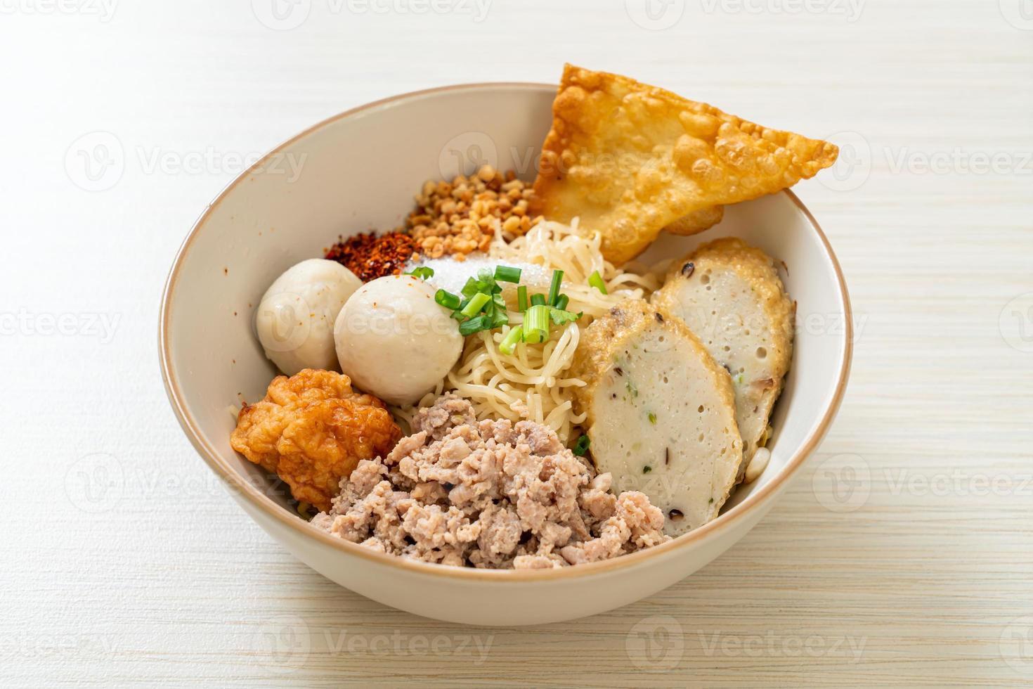 Fideos de huevo picantes con bolas de pescado y bolas de camarones sin sopa - estilo de comida asiática foto