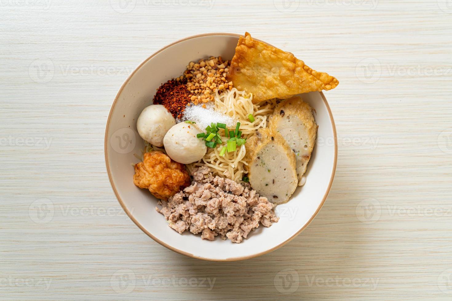 Fideos de huevo picantes con bolas de pescado y bolas de camarones sin sopa - estilo de comida asiática foto