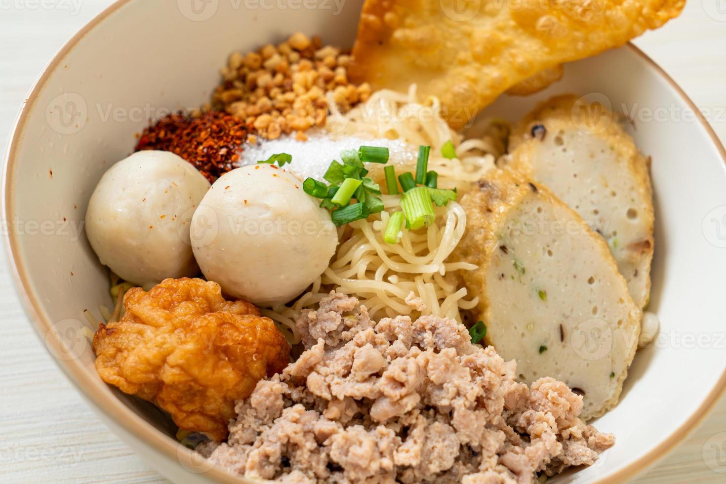 Fideos de huevo picantes con bolas de pescado y bolas de camarones sin sopa - estilo de comida asiática foto