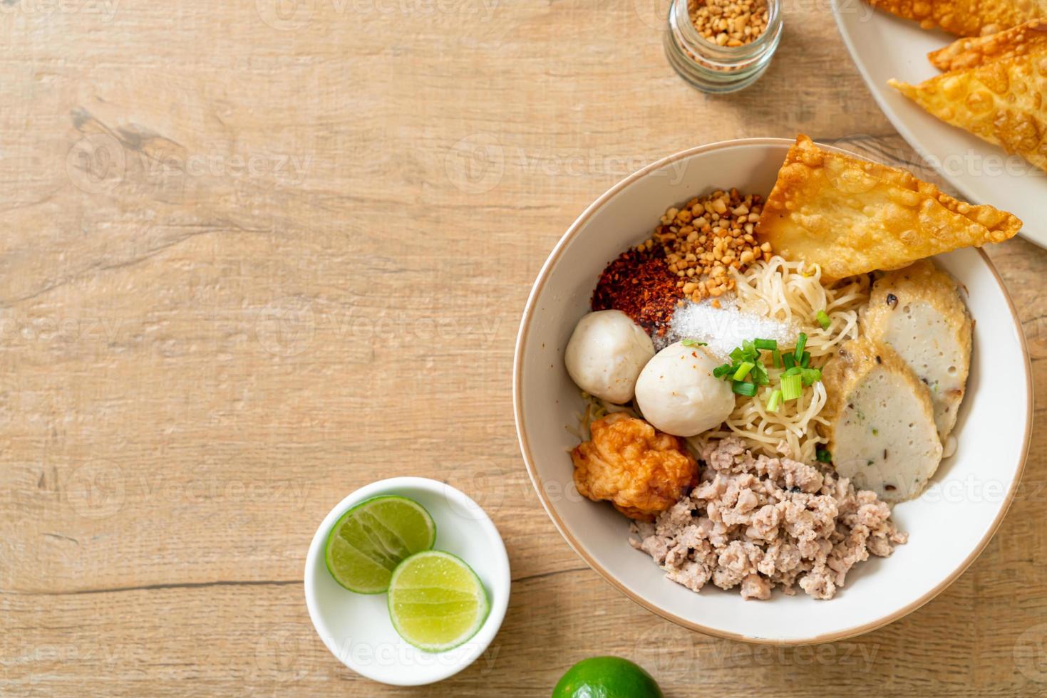 Fideos de huevo picantes con bolas de pescado y bolas de camarones sin sopa - estilo de comida asiática foto