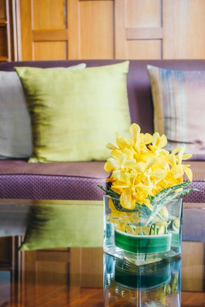 Florero de flores en la mesa con una almohada en el sofá foto