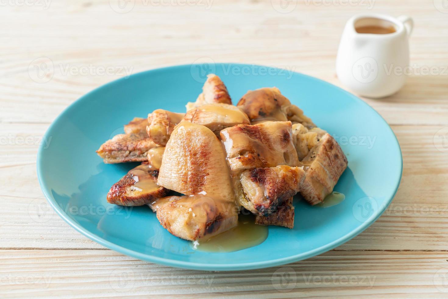 Plátanos asados con salsa de caramelo de coco en la placa foto