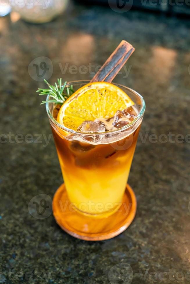 refresco de jugo de naranja y limón cubierto con café negro en vaso con romero y canela foto